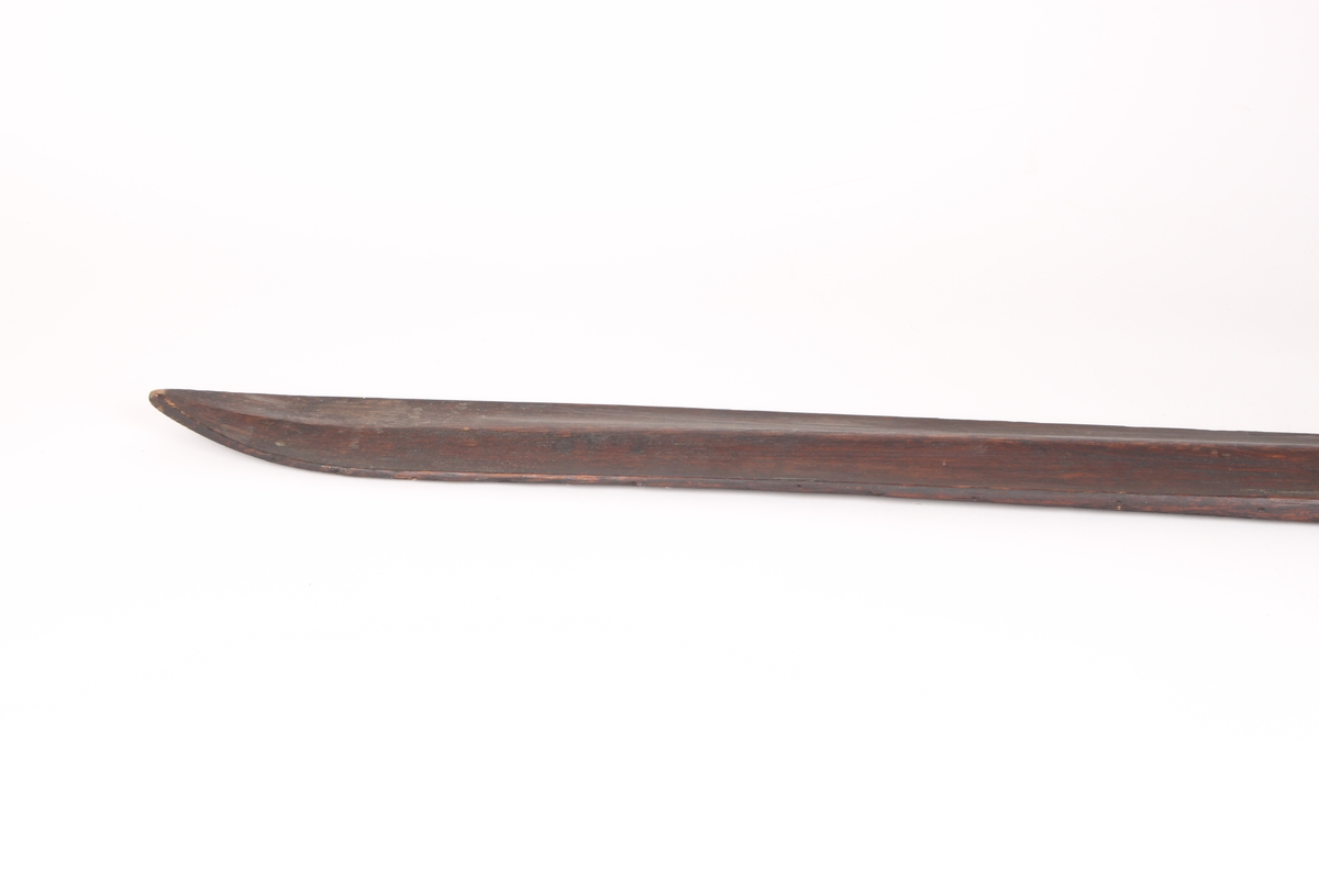 Et par ski, trolig i ask. Framskien er avsmalnende og bakskien er jevnbred. Skiens forende har en profilert tupp, type nese. Bakskien ender i en oppbøyd spiss. Skiens overside har en møneformet rygg med hulkil, og en dyp midtrand under. 
Bindingen er i skinn, festet med tau. Fotstegplaten i bjørkenever er festet med metallstifter.