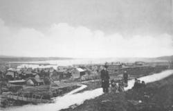 Syv personer foran en bygd. To voksne og fire barn på den gr