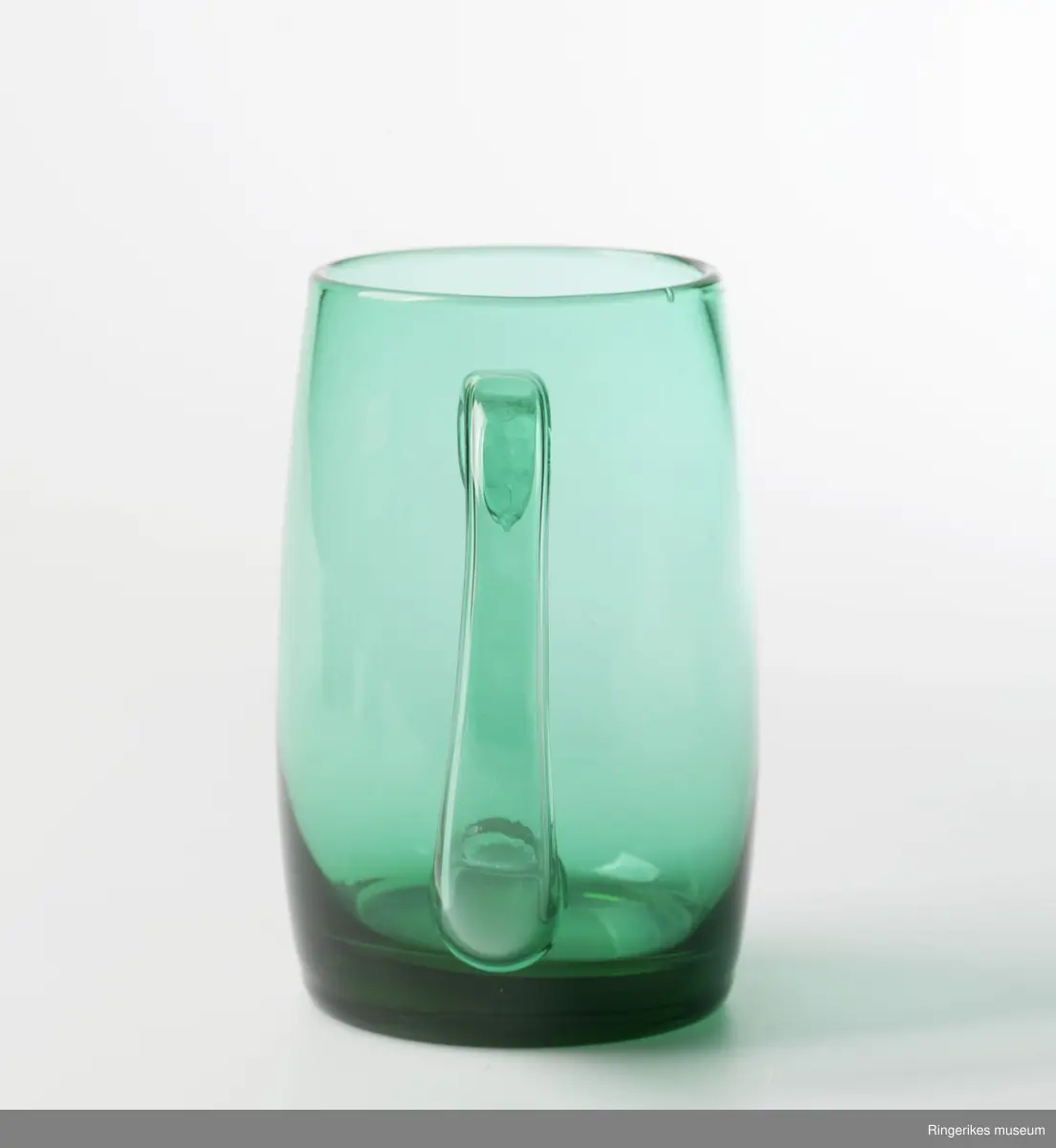 Fire like glass i form og størrelse, To farger. sylinderformet med konvekst midtparti, Buet - C-formet  hank. Designglass fraHadeland glassverk i egen serie og svært populært på 1970-tallet. Mest brukt til øl.