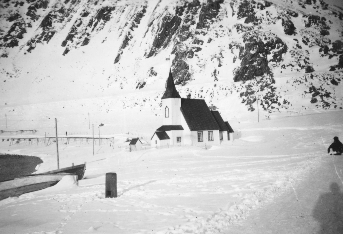 Kirken i Kjøllefjord. Noen båter ligger opptrekt. Snøen ligger på bakken og i fjellet