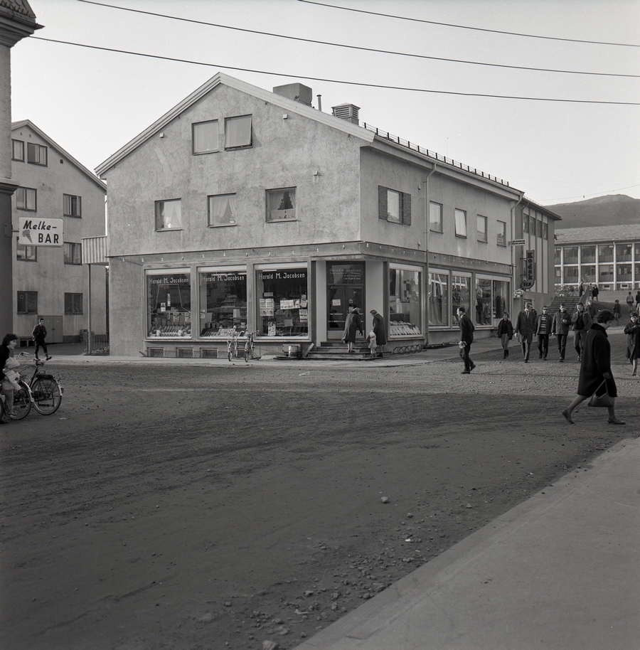 Harald M. Jacobsens forretningsgård på Sortland ca. 1966. Krysset mellom Kjøpmannsgata og Rådhusgata. Rådhuset i bakgrunnen til høyre.