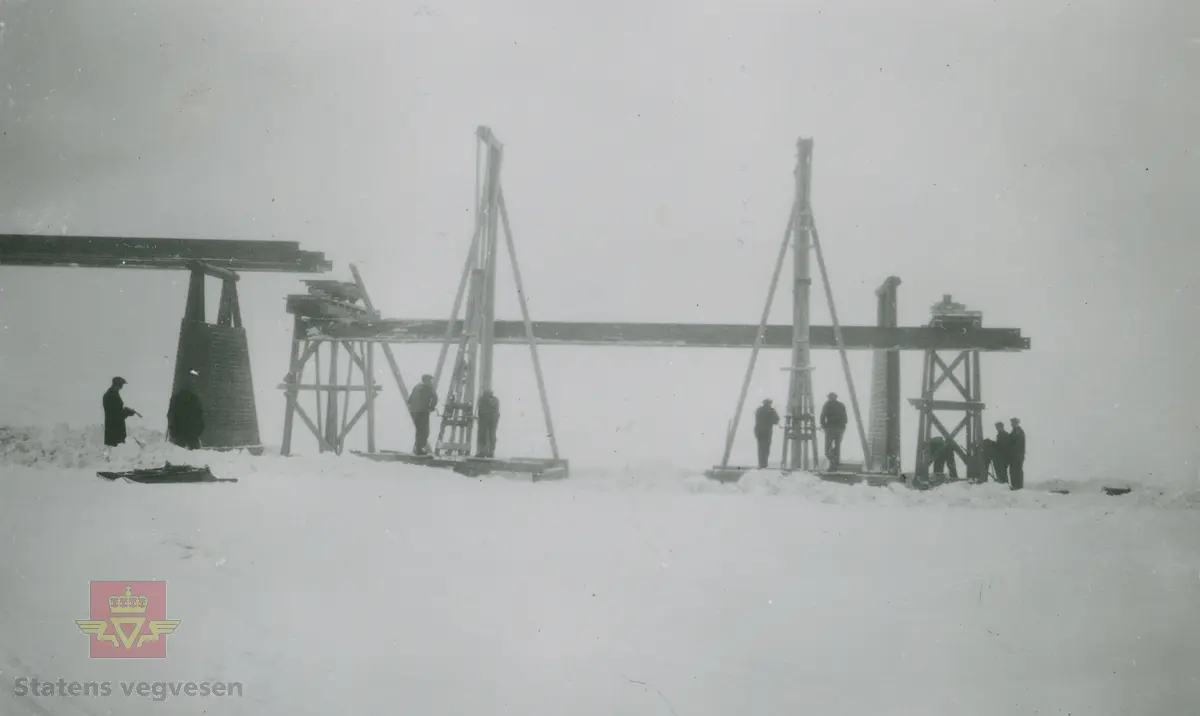 Album fra 1929-1943. Lia bru over Ottaelva i Lom  1942. Brubygging i vinterhalvåret. Pelemaskin i bruk for nedslåing av  pæler.