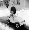 Tom Andersson i lådbilen en vinterdag på Odengatan 22 i Huskvarna. Bakom honom står flickan Nelson.