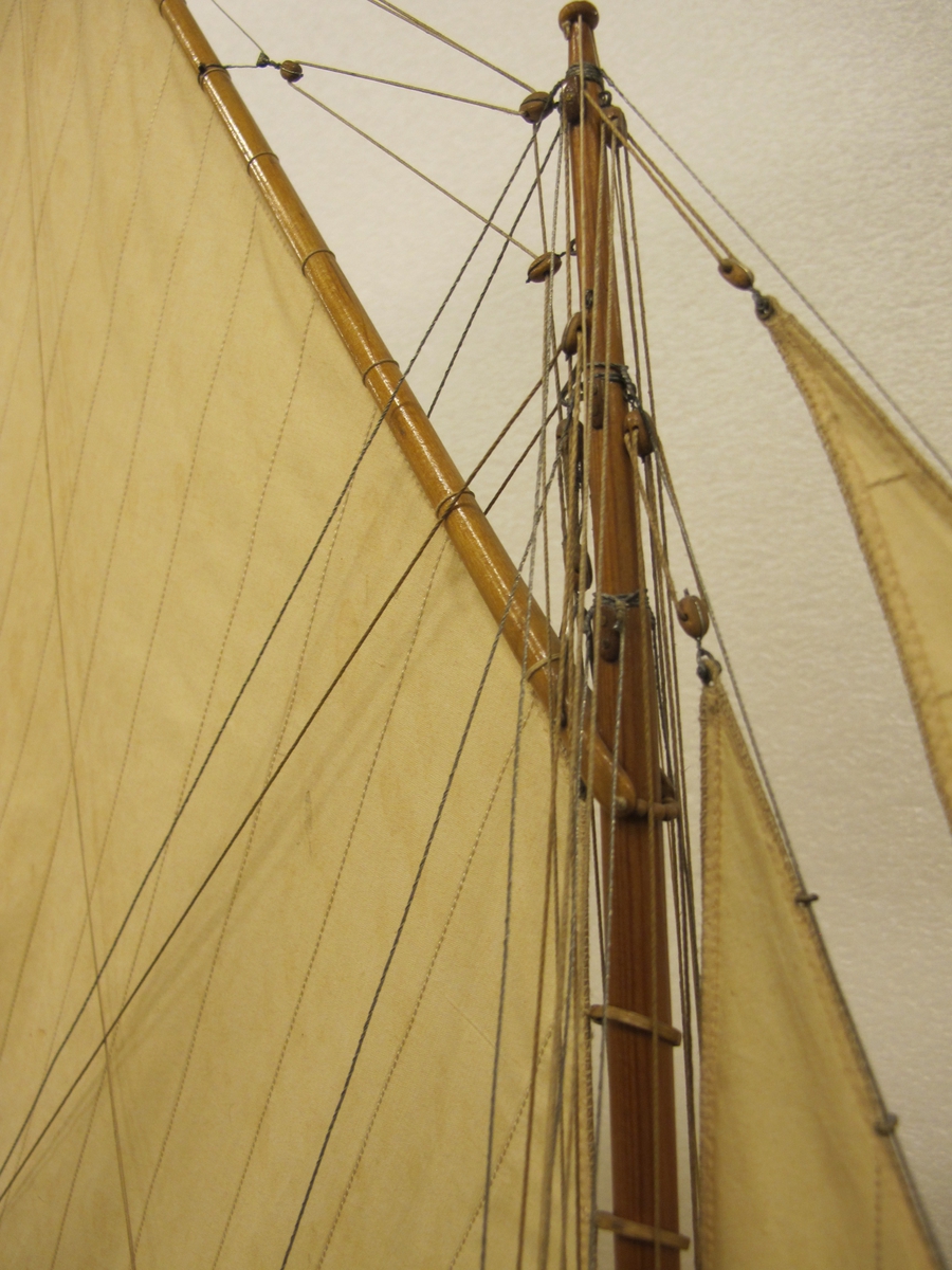 Segelkutter, skärgårdskryssaren ALCA. Fullständigt inredd med kajuta och sittrum. Modell byggd i ett trä. Riggad. Mast i en längd med gaffelsegel, fock och klyvare. Flagga och igenkänningsstandert. Vitmålad, röd botten. Fernissat däck och inredning. Stativ fernissat och förgyllt.
Alca var  45, 2 fot lång och 8,9 fot bred