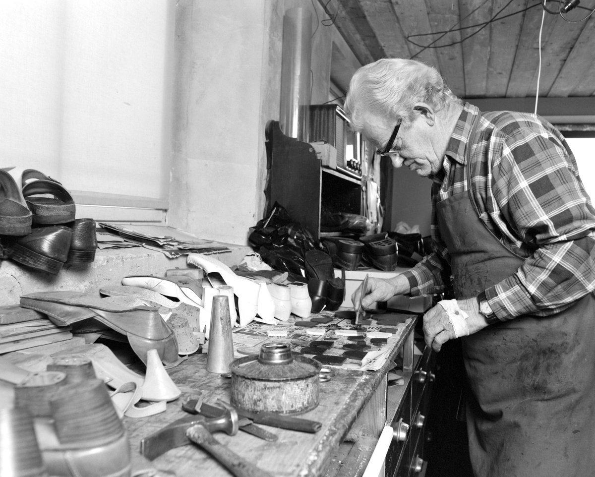 Skomaker Kristian Helgesen, Løten. Ved arbeidsbenken i verkstedet. Holdt til ved Borgkrysset, i krysset Ådalsbrukvegen-Rokosjøvegen. Hans firma het "Kvikk Vulk", han tok over i 1946, et firma som var etablert under krigen,
