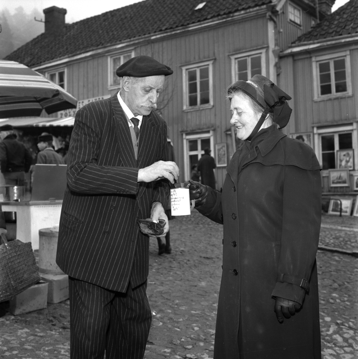 Ernst Wibeck lämnar ett bidrag till frälsningssoldat Ester Öhman på Gränna marknad.