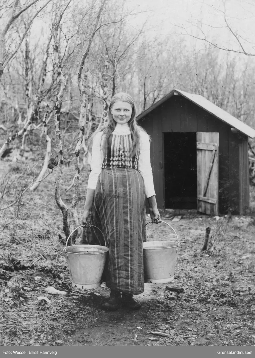 Kvenpiken Nanna Elmina Vartiainen fra Neiden var tjenestepike hos Wessels, her fotografert ved brønnhuset på doktorgården Solheim, Kirkenes 1896.