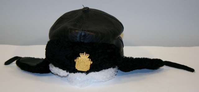 Uniform for politinspektør etter 1963-reglement med merking etter 1977-reglement. Helårsuniform M/1963 med skjorte, langbukse, belte, helårskappe og jakke. Skyggelue med gullbrodert bånd, loslue og båtlue M/1967. Kappen og jakken har skulderklaffer av flettede gullsnorer med to sølvstjerner og festeknapp i gullbroderi. Skjorten har en enklere skulderklaff med to gule render og to sølvstjerner. Det følger med et ekstra enkelt lærbelte og et ekstra sett skulderklaffer til skjorte. Plaggene har gullfargede løveknapper.