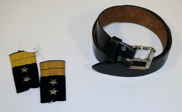 Uniform for politinspektør etter 1963-reglement med merking etter 1977-reglement. Helårsuniform M/1963 med skjorte, langbukse, belte, helårskappe og jakke. Skyggelue med gullbrodert bånd, loslue og båtlue M/1967. Kappen og jakken har skulderklaffer av flettede gullsnorer med to sølvstjerner og festeknapp i gullbroderi. Skjorten har en enklere skulderklaff med to gule render og to sølvstjerner. Det følger med et ekstra enkelt lærbelte og et ekstra sett skulderklaffer til skjorte. Plaggene har gullfargede løveknapper.