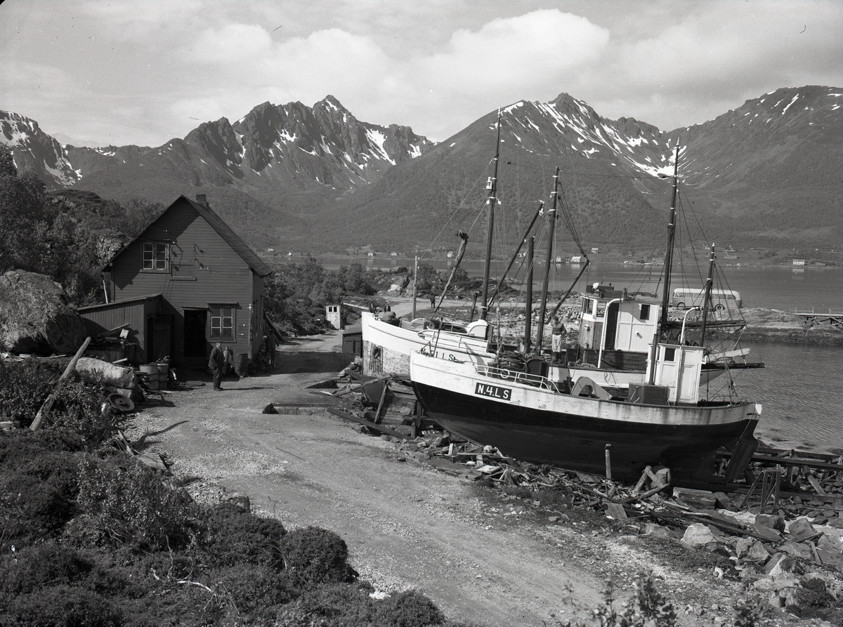 Slippen og kaia på Holm ca. 1952. Holm lå på denne tida i Langenes kommune, men ble senere overført til Sortland. Ifølge Merkeregisteret for 1952 er båtene N-4-LS MS Arnold og N-61-LS MK Solbris. Bussen fra Sortland korresponderte med rutebåten over Lifjorden til Toftenes.

Opplysning fra seer: Bildet kan være tatt av Ivar Toften.