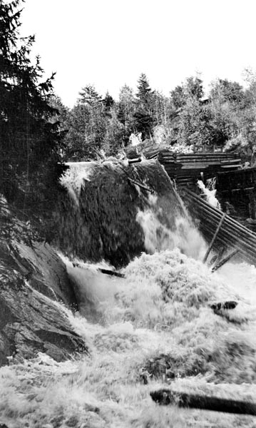 Bergsfossen i Austvassåa i Nord-Odal kommune i Hedmark.  Fotografiet er tatt i motstrøms retning mot et fall i elva der vatnet ble ledet utfor fossen over en terskel inntil nordre bredd.  På sørsida ser det ut til å ha vært en slags tømmerkistekonstruksjon på oversida av det nevnte fallet og en tømmerskjerm på nedsida.  Sannsynligvis var sørsida av fossen (til høyre) på bildet tilrettelagt for et kvernbruk, den såkalte Bergekverna, som ikke er med på fotografiet.  Opptaket er gjort på et tidspunkt da fløterne hadde åpnet ovenforliggende dammer, slik at vannføringa var større enn vanlig.  Vi ser også en del tømmerstokker, både i sjølve fossen og i strømkavet nedenfor.  Vi aner kreftene i fossefallet, som kunne gjøre skade på en del av fløtingstømmeret som passerte.   Austvassåa kommer fra Nøklevatnet i grensetraktene mellom Odalsbygdene, Hoff og Grue.  Vassdraget er om lag 17 kilometer lang, og passerte flere små vatn på sin veg mot utløpet i Storsjøen.  Det ble fløtet tømmer på hele strekningen mellom Nøklevatnet og Storsjøen.  Omkring 1900 var det fem fløtingsdammer i Austvassåa.  Når alle dammer var i orden, var Austvassåa «sikker til første års utkomme», noe som betydde at tømmeret herfra vanligvis nådde hovedvassdraget og lenseanleggene der det samme år som det ble «annammet» på velteplassene i odalsskogene.