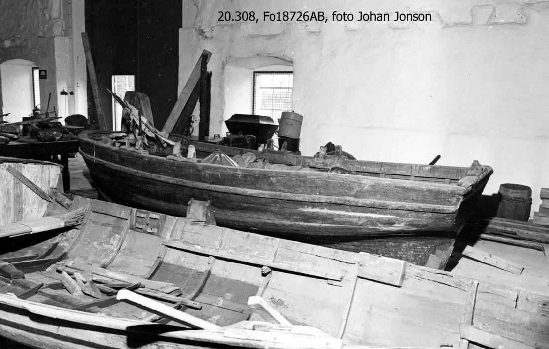 Kravellbyggd roddbåt i ek. 2 par fasta, öppna korsvis ställda årtullar. Järnband längst relingen. 3 tofter+1 i akter. Ej durk. Sudband. Plattgattad.