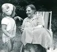 Sommaren 1955. Veronika i vit hätta med rosor. Judit Abrahamsson i klänning i franska flaggans färger. Sparkdräkten i ljusgult stickad av Birgit, babydockan ärvde den.