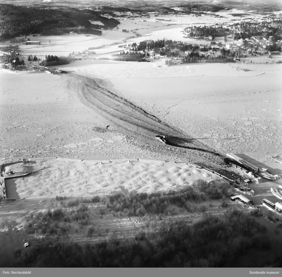 Flygfoto över Alnösundet med färjelägena på Alnö och i Fillan. Däremellan är Alnöfärjan på väg i isrännan.Till höger Johannedal och längre upp radiomasterna i jordbrukslandskapet där numera (2015) Birsta köpcentrum breder ut sig.