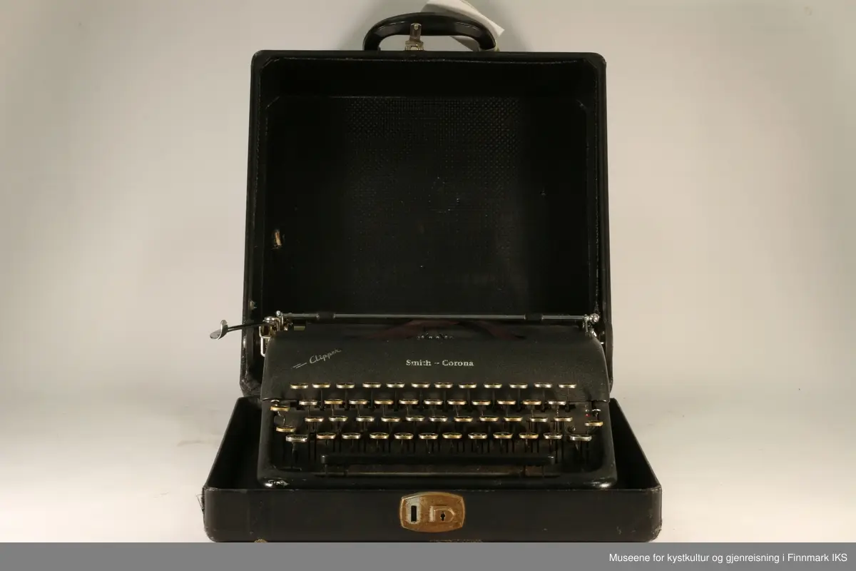Sort reiseskrivemaskin i koffert. Av merket Smith-Corona, modell Clipper med norsk tastatur.

Kofferten er sort, har håndtak i plast og lås av metall (nøkkel mangler).