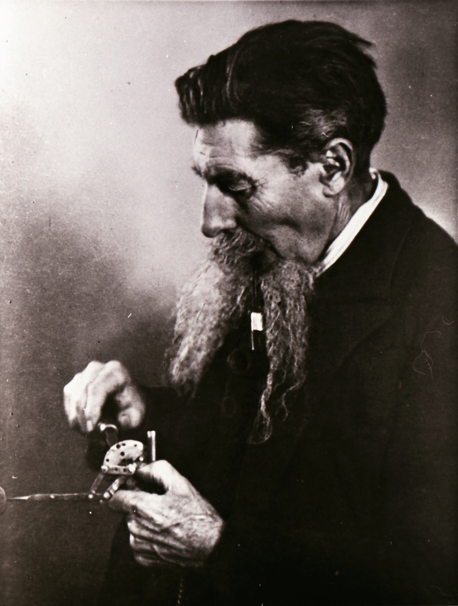 Portrett av en mann som finstiller et instrument/ apparat.