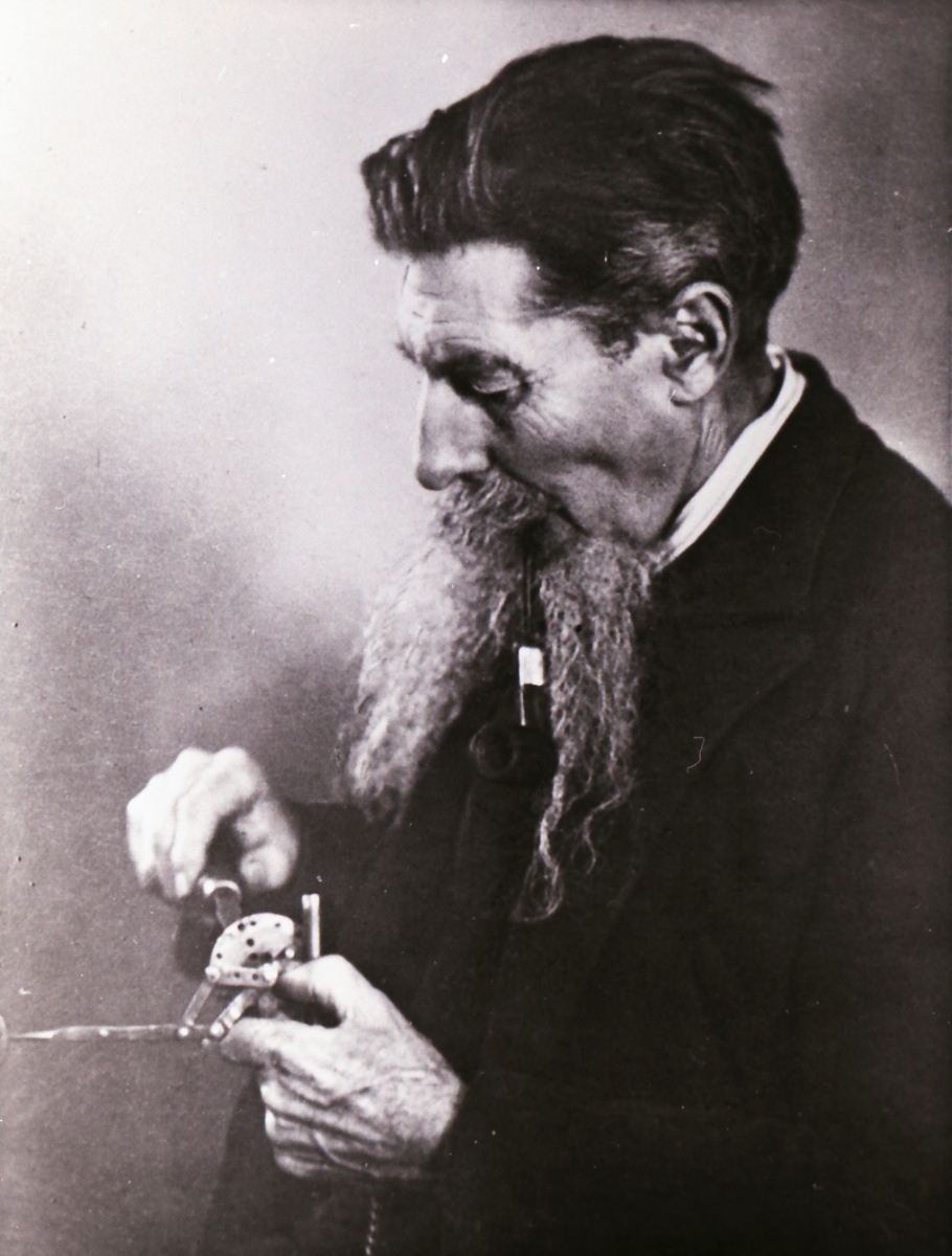 Portrett av en mann som finstiller et instrument/ apparat.