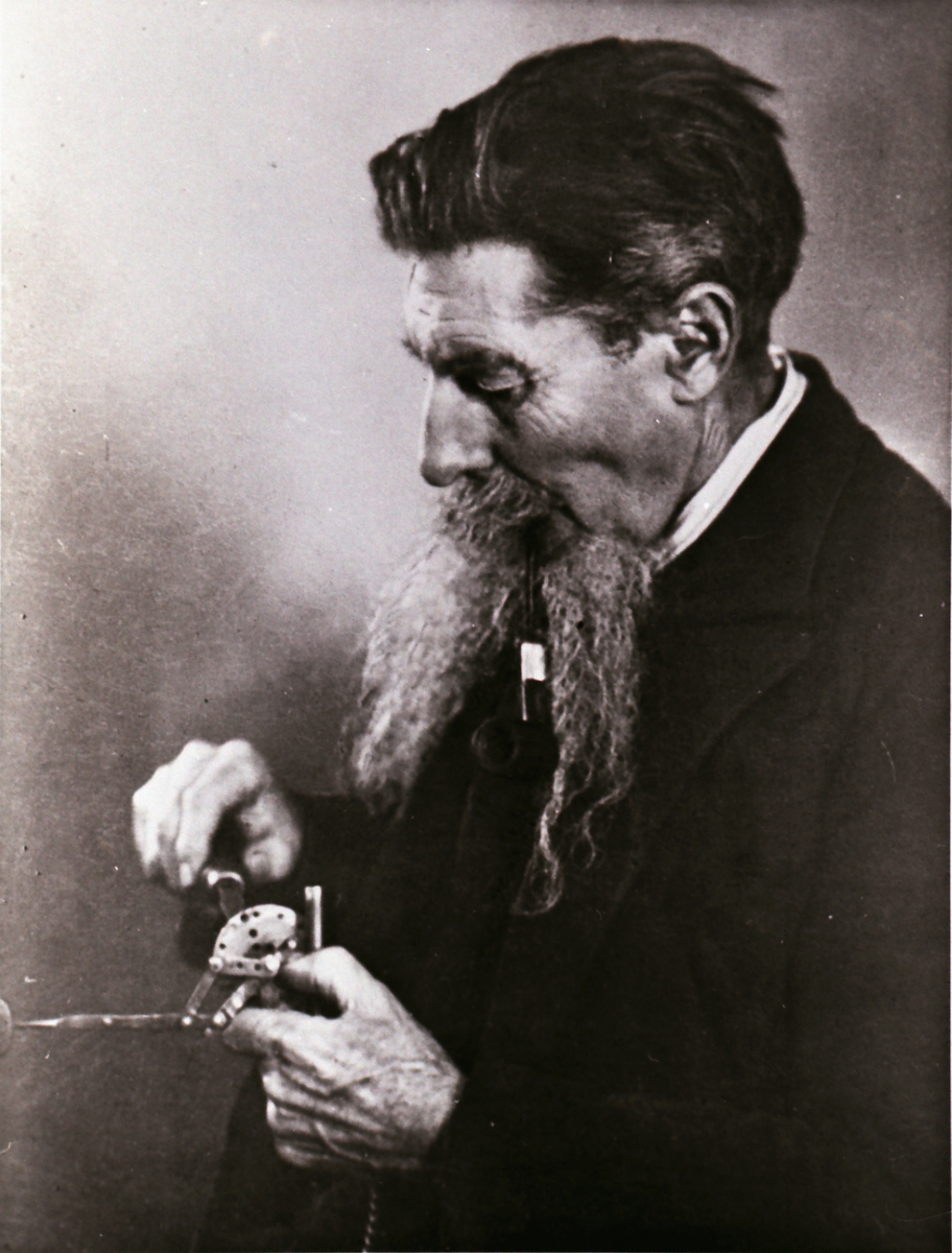 Portrett av en mann som finstiller et instrument/ apparat.