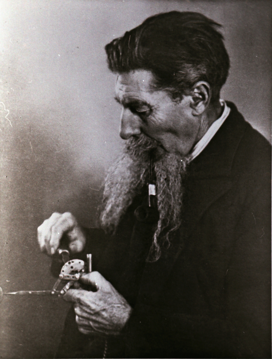 Portrett av en mann som finstiller et instrument/ apparat.