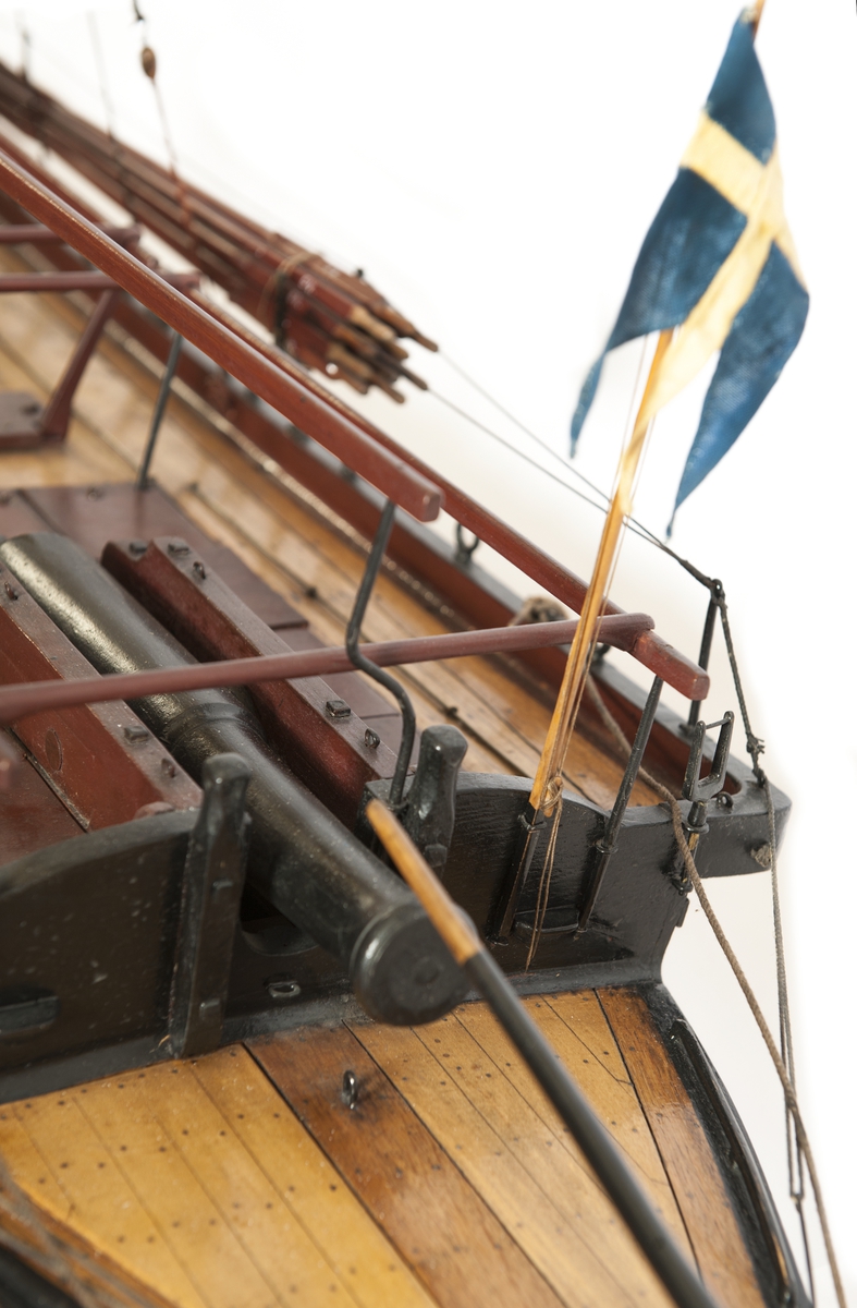 Båtmodell, däckad kanonjolle 1788 års typ. Riggad med två loggertsegel, flagga och spel, vimpel och gösstake. Bordlagd på spant, kravell med inredning. Utdragen akter, tältstomme. 10 par årtullar, 20 st åror, 1 styråra. Roder med rorpinne. Fernissad med svart/vit reling. Bruna åror, däcksluckor och lavetter. 2 träkanoner. 2 fernissade skrå.
Nytt skrå 1938. En grov kanon akterut, en nicka förut. En man vid åran.