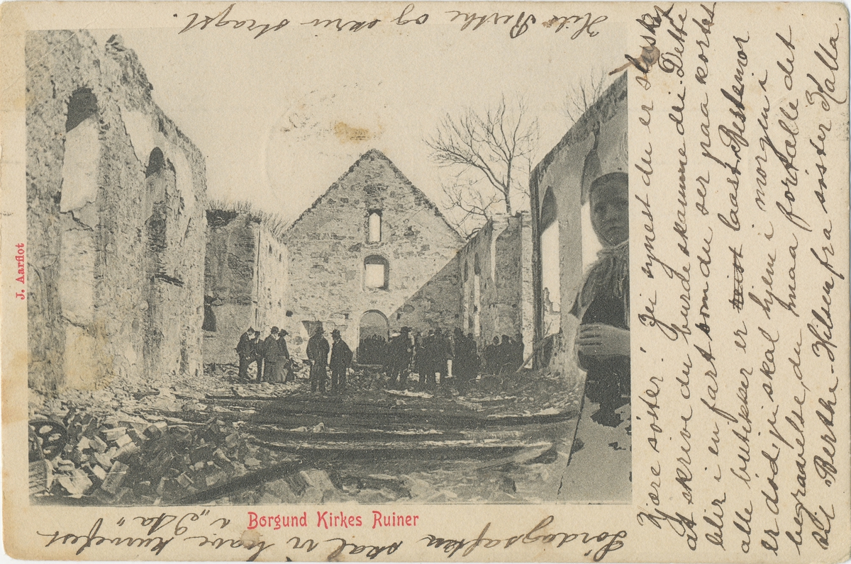 Borgund kirke i ruiner etter brannen 1904. Motiv fra innsiden der en gruppe mennesker er samlet.
