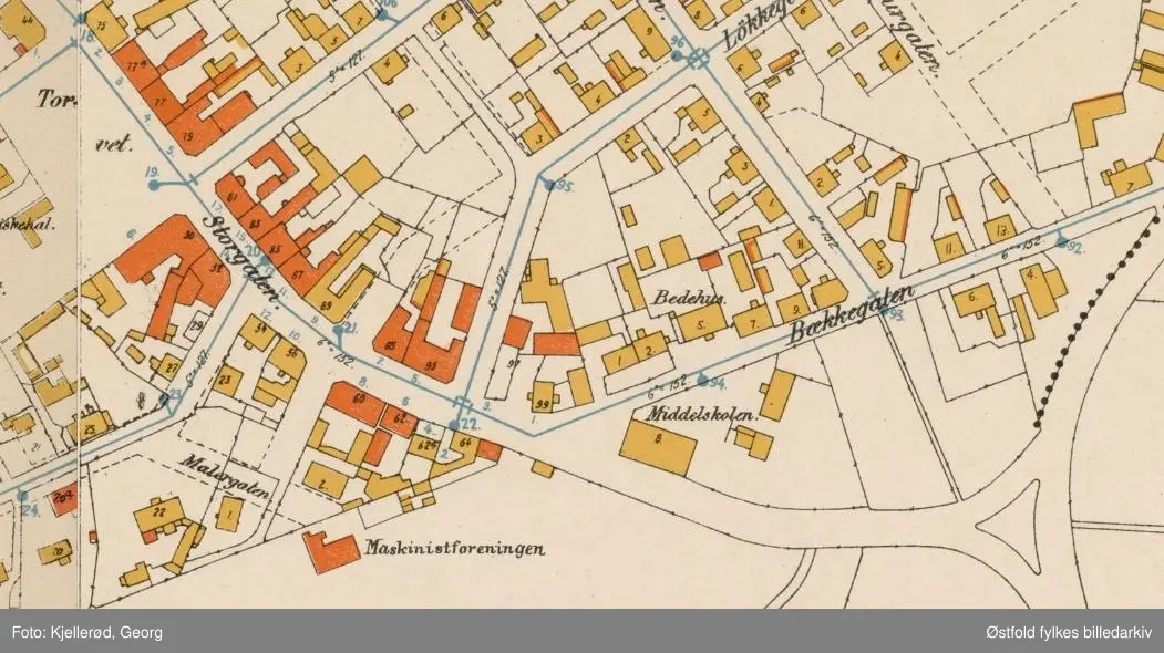 Horten med bygning for telefon og telegraf i Storgata. 

Helt til venstre: Helga Beck, kiosk med reklame for "Tobak & Cigarer" på taket. Helga Beck startet sin butikk 22. oktober 1907 skriver Johan Beck (1911) med tilhørende bilde av nettopp denne tobakksforretningen (lengst unna i bildet). 

Borreminne skriver at telefonsentralen var plassert nederst i Storgata i bakermester Olsens gård (murbygningen avbildet). 

Bygningen i midten ser ut til å være et bakeri.
Folketelling 1910 forteller at Henry Grøstad var bakeren som hadde tilhold her, i 1910 var adressen Storgata 64, senere omgjort til dagens Storgata 2.