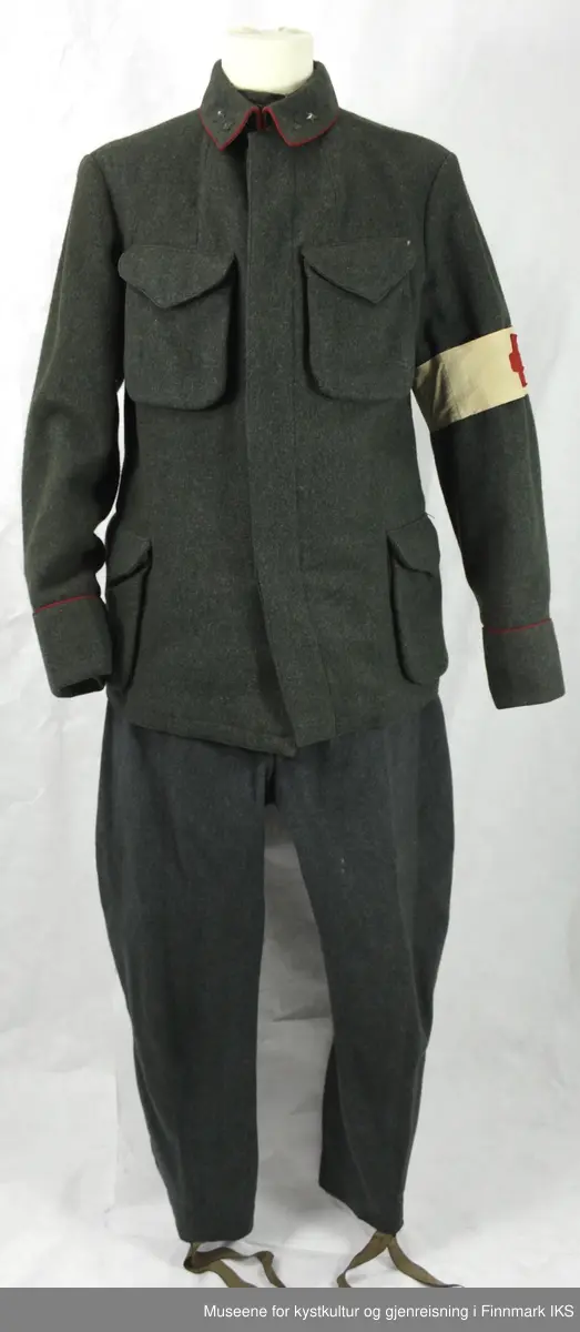 Uniformen besto opprinnelig av lue, jakke, bukse, belte og lærstøvler. Beltet og støvlene mangler. Uniformen består av mørkegrønn vadmel og har smale røde kanter ved yttersømmen til buksen, kragen og ved mansjettene. Luen / hatten har to parallelle gule striper rundt og på for- og baksiden. På fremsiden befinner seg en reim og et skjold som er svarte. På jakkens vestre armen er det festet en armbind med genferkors. Jakken lukkes med skjulte knapper i kunststoff . Den har to brystlommer og to sidelommer med klaff samt to metallhemper ved kragen. På innsiden til venstre befinner deg atter to lommer uten klaff. Jakken er foret med lyst, ubleket bomullsstoff. Den lange buksen er formet vid rundt lårbeinene, har to sidelommer og stropper nede. Den er en høy modell med knapper til seler og spensel i rygg. Buksen har en skult knepping i gylfen med metallknapper og en metallhempe øverst. Klærne er stemplet på innsidene.