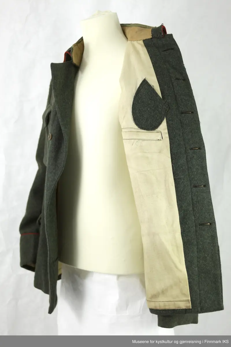 Uniformen besto opprinnelig av lue, jakke, bukse, belte og lærstøvler. Beltet og støvlene mangler. Uniformen består av mørkegrønn vadmel og har smale røde kanter ved yttersømmen til buksen, kragen og ved mansjettene. Luen / hatten har to parallelle gule striper rundt og på for- og baksiden. På fremsiden befinner seg en reim og et skjold som er svarte. På jakkens vestre armen er det festet en armbind med genferkors. Jakken lukkes med skjulte knapper i kunststoff . Den har to brystlommer og to sidelommer med klaff samt to metallhemper ved kragen. På innsiden til venstre befinner deg atter to lommer uten klaff. Jakken er foret med lyst, ubleket bomullsstoff. Den lange buksen er formet vid rundt lårbeinene, har to sidelommer og stropper nede. Den er en høy modell med knapper til seler og spensel i rygg. Buksen har en skult knepping i gylfen med metallknapper og en metallhempe øverst. Klærne er stemplet på innsidene.