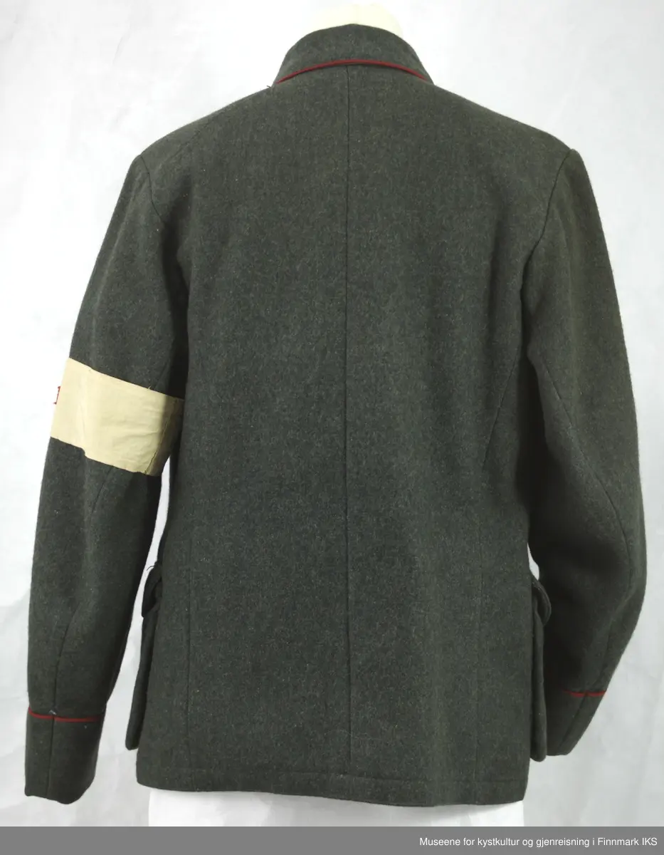 Uniformen besto opprinnelig av lue, jakke, bukse, belte og lærstøvler. Beltet og støvlene mangler. Uniformen består av mørkegrønn vadmel og har smale røde kanter ved yttersømmen til buksen, kragen og ved mansjettene. Luen / hatten har to parallelle gule striper rundt og på for- og baksiden. På fremsiden befinner seg en reim og et skjold som er svarte. På jakkens vestre armen er det festet en armbind med genferkors. Jakken lukkes med skjulte knapper i kunststoff . Den har to brystlommer og to sidelommer med klaff samt to metallhemper ved kragen. På innsiden til venstre befinner deg atter to lommer uten klaff. Jakken er foret med lyst, ubleket bomullsstoff. Den lange buksen er formet vid rundt lårbeinene, har to sidelommer og stropper nede. Den er en høy modell med knapper til seler og spensel i rygg. Buksen har en skult knepping i gylfen med metallknapper og en metallhempe øverst. Klærne er stemplet på innsidene.