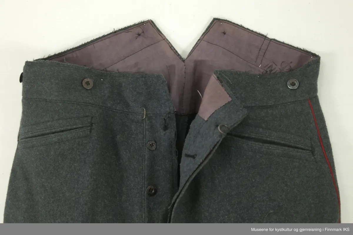 Uniformen besto opprinnelig av lue, jakke, bukse, belte og lærstøvler. Beltet og støvlene mangler. Uniformen består av mørkegrønn vadmel og har smale røde kanter ved yttersømmen til buksen, kragen og ved mansjettene. Luen / hatten har to parallelle gule striper rundt og på for- og baksiden. På fremsiden befinner seg en reim og et skjold som er svarte. På jakkens vestre armen er det festet en armbind med genferkors. Jakken lukkes med skjulte knapper i kunststoff . Den har to brystlommer og to sidelommer med klaff samt to metallhemper ved kragen. På innsiden til venstre befinner deg atter to lommer uten klaff. Jakken er foret med lyst, ubleket bomullsstoff. Den lange buksen er formet vid rundt lårbeinene, har to sidelommer og stropper nede. Den er en høy modell med knapper til seler og spensel i rygg. Buksen har en skult knepping i gylfen med metallknapper og en metallhempe øverst. Klærne er stemplet på innsidene.