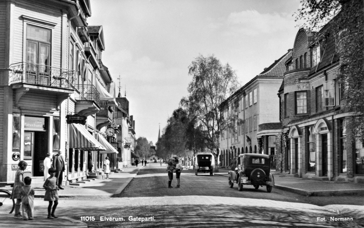 Postkort, Elverum, gateparti, Storgata, bygninger, folk, biler, personbil  Ford A 1930-31 registreringsnummer D-3370.