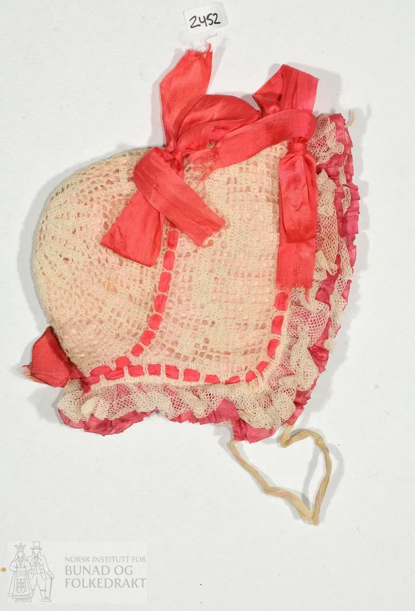 Lue i heklet bomull med bomullslerret i for. Rynket blonder i tyll foran. 

Lengde fra øre til øre:
1. over nakken: 28cm.
2. over panna: 21cm.
Tvers over: 25cm