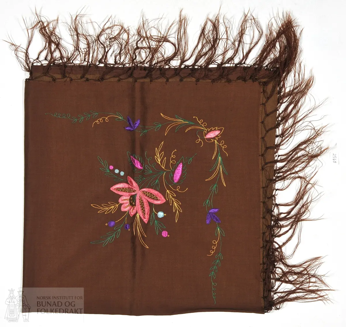 Silkesjal, brunt, med brune frynser. Brodert med silkegarn i flere farger. Stoffet er i sateng med bomull i renning og silke i innslag. 72x72cm.