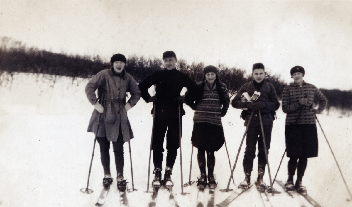 Fem unge kvinner og menn på skitur.