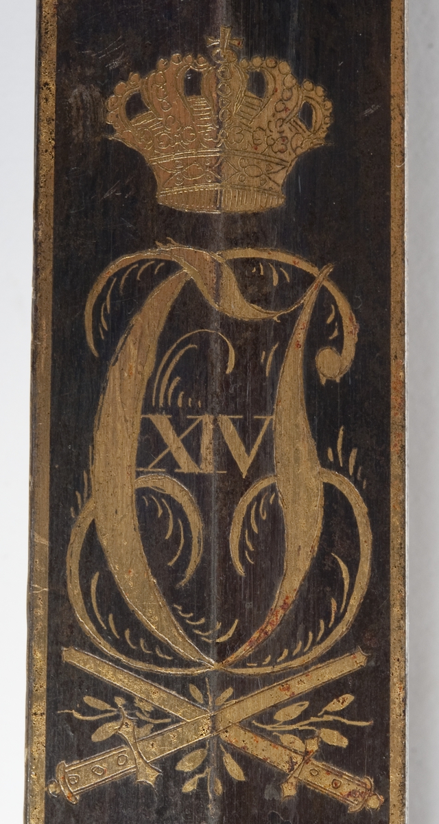 En kårde m/slire.
Gallakårde efter O. E. Holck, stål m/messingbeslag, skjeftet m/løveh. dekorert med Carl Johan XIV's riksvåpen og løve, hengslet parerplate.  1. repr. Bergenhuiske infanteriregiment.