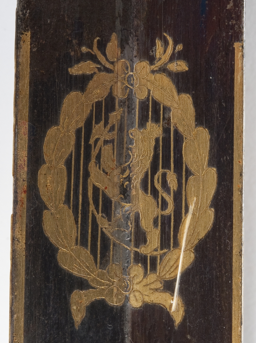 En kårde m/slire.
Gallakårde efter O. E. Holck, stål m/messingbeslag, skjeftet m/løveh. dekorert med Carl Johan XIV's riksvåpen og løve, hengslet parerplate.  1. repr. Bergenhuiske infanteriregiment.