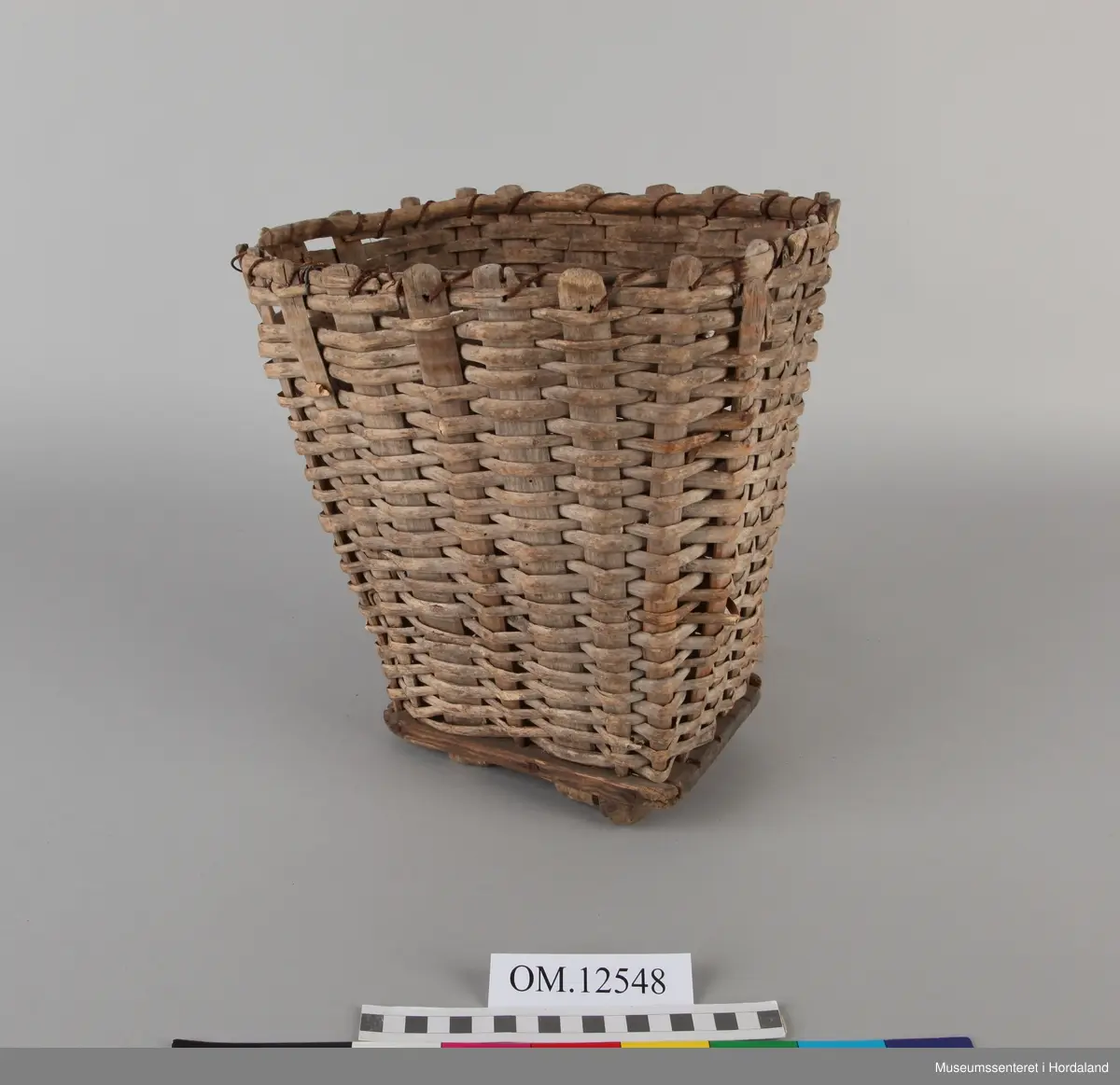 Lita barnekipe med tett fletting. Både breie og smale stakar. Tegene til flettinga er runde på utsida (halv grein). Den eine "foten" er borte. Lealaus og ein del avknekte tegeendar. Streng oppe rundt kanten til forsterking ved bandet. Nokre jarnstifter under. Hampetau til skulderreimer.