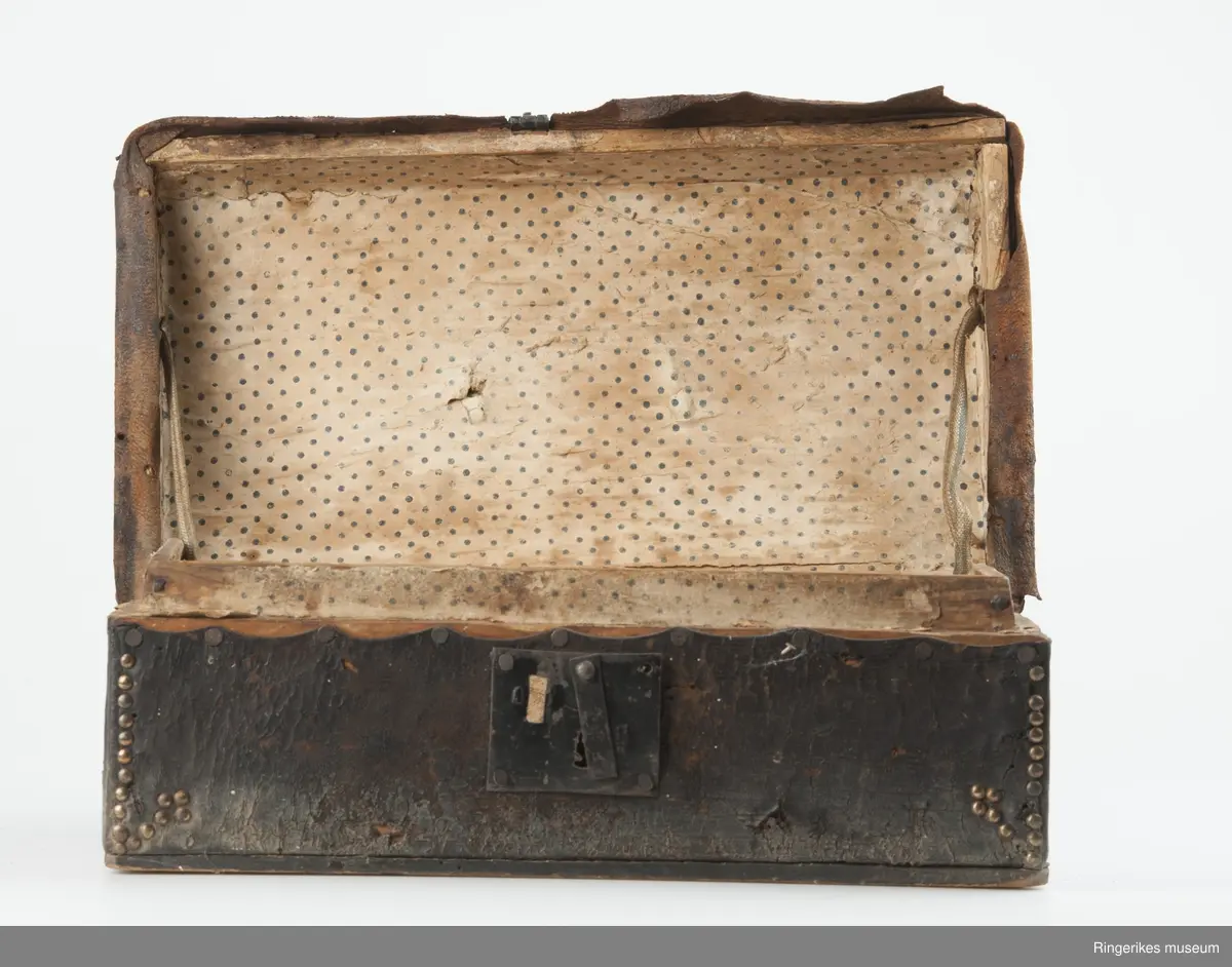 innslåtte kobbernagler langs kante rog hjørner på kasse og lokk som dekor. Prikkei mønster på papir.