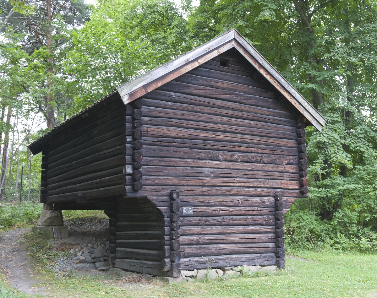 KJONE FRA KARSRUD I VÅLE, CA. 1835 
Overført til museet 1935, gjenoppført 1936 

I kjona ble det tørket korn, lin og hamp. Denne kjona er spesiell fordi det i første etasje, som ble kalt «omnshuset», var et lite ildsted midt på gulvet, istedenfor den mer vanlige badstuovnen. I andre etasje var det karmer med spiler over – «karma» med «spili» – der avlingen ble lagt for å tørkes. Varm luft og røyk trengte opp fra omnshuset gjennom en åpning mellom karmene. 

(Tekst hentet fra By og bygd 43, 2010)