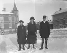 Tre ungdomar i en snöig stadsdel.