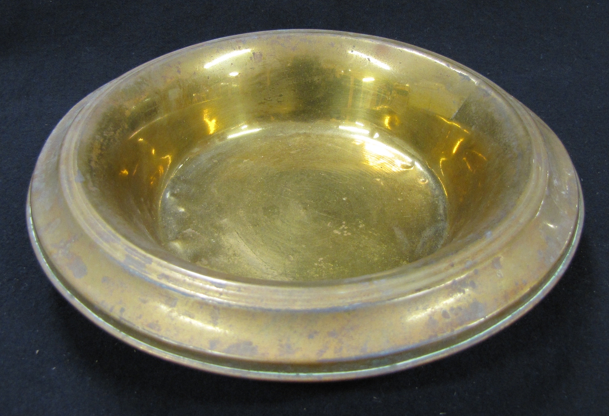 Spottkopp av mässing. Som lock användes ett vitt fat i porslin se VM18769:b.

160 mm. i diam.

Spottkoppen stod i skomakarverstad som ägdes av skomakarmästare Karl Gustav Lundell 1858 - 1923 (far till givaren).