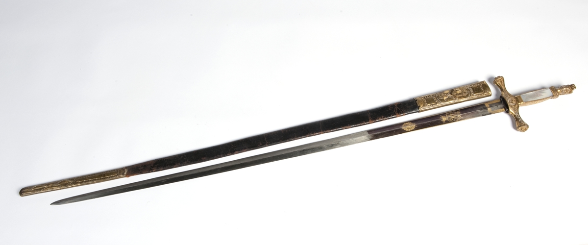 Perlemors-håndtak.  Skjefte m/visirhode, soldat m/gevær, riksvåpen.  Klingen signert " C. M. F. " og  " C XIV J ".
Sliren av lær og messing, liljemerket.