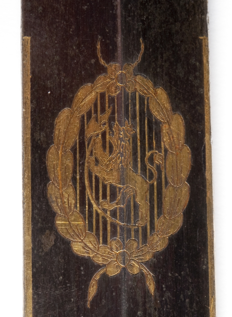 Perlemors-håndtak.  Skjefte m/visirhode, soldat m/gevær, riksvåpen.  Klingen signert " C. M. F. " og  " C XIV J ".
Sliren av lær og messing, liljemerket.