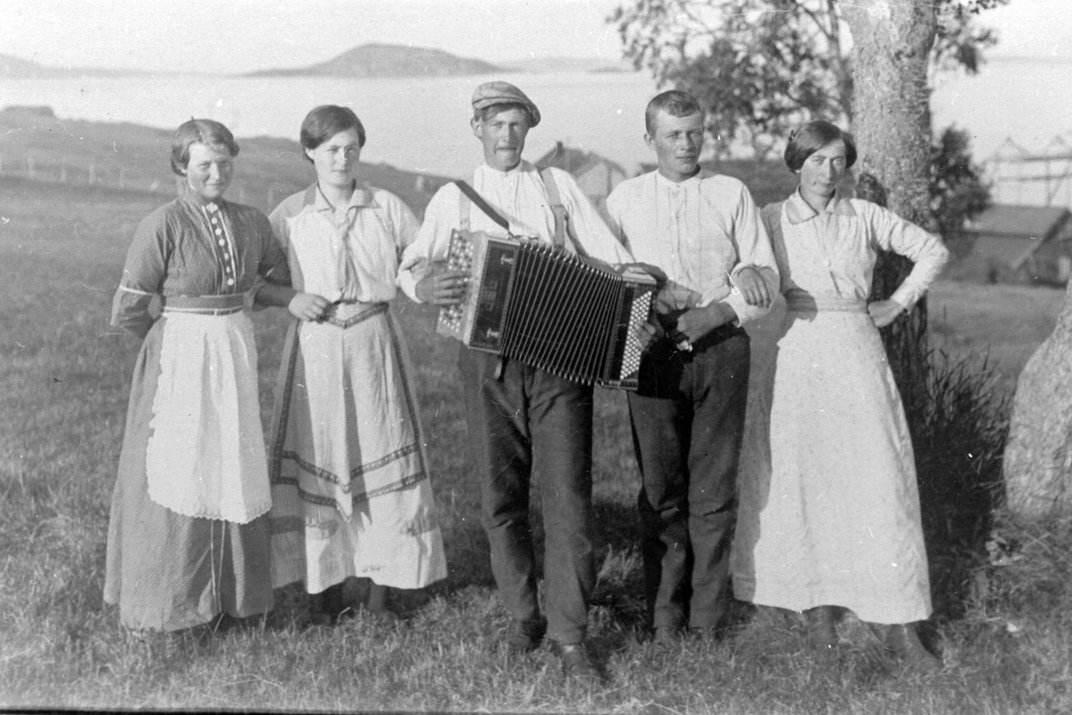 Gruppebilde av tjenestefolk på Røkenes gård. En av dem har trekkspill.