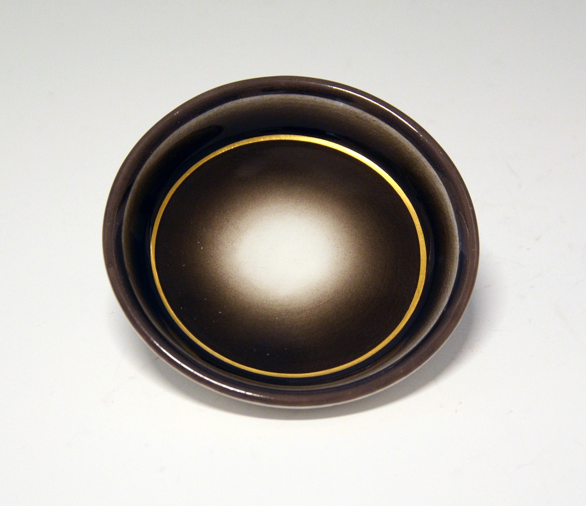 Liten, rund skål i porselen. Sort dekor med gullring. Hører sammen med NJT.0459.
Dekor: 609.
Kunstner Nora Gulbrandsen 1927-35.