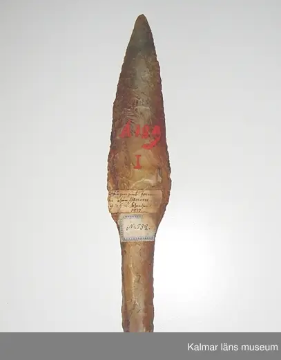 KLM 552. Dolk. Av gulbrun flinta. Senneolitisk tid. Bladet är parallellhugget och insvängt ned mot skaftet. Oskadad. Äldre märkning: A 189 I.