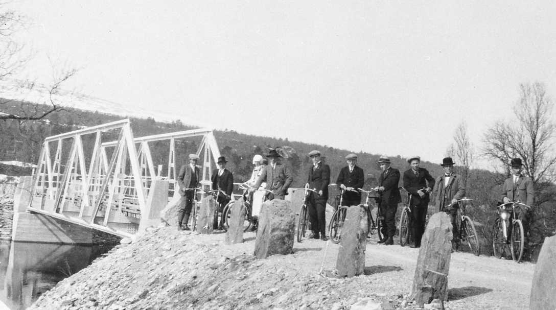 Personer med sykler på bro. Narjordsungdom på heimveg en kirkesøndag ca 1923. 