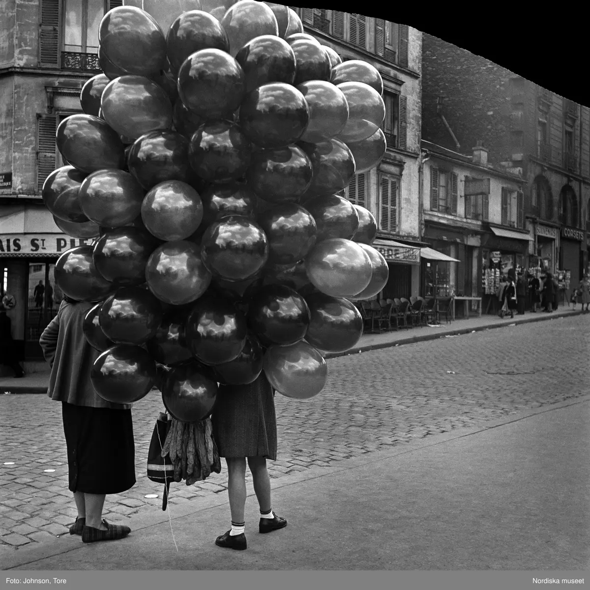 Paris. Kvinna och flicka dolda bakom ett stort knippe ballonger.