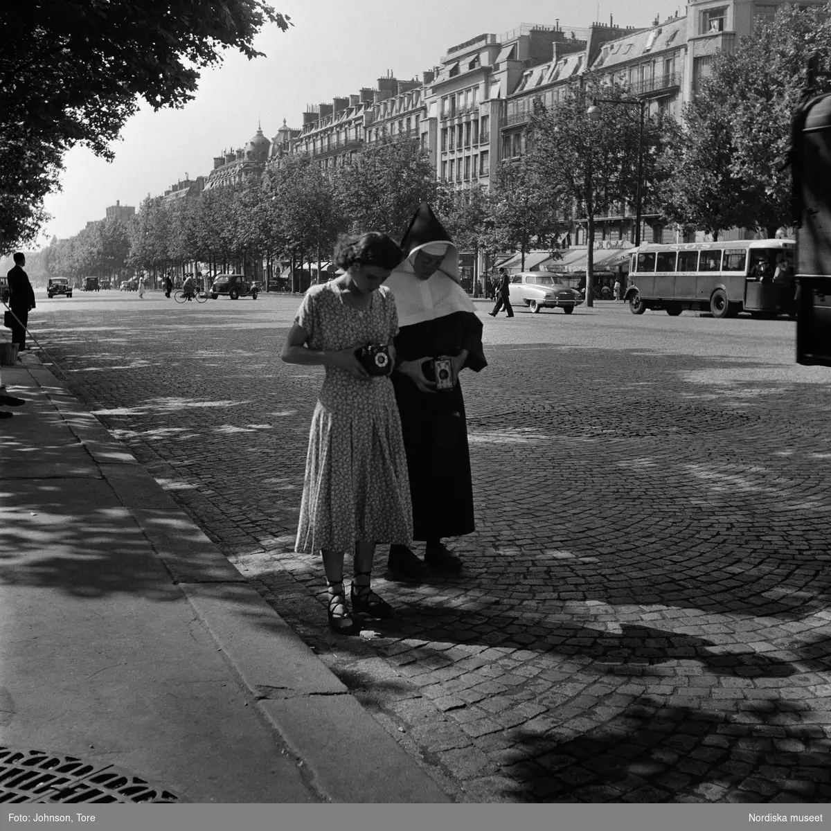 Paris. Två kvinnor, den ena i nunnedräkt, tittar i sökaren på varsin kamera.