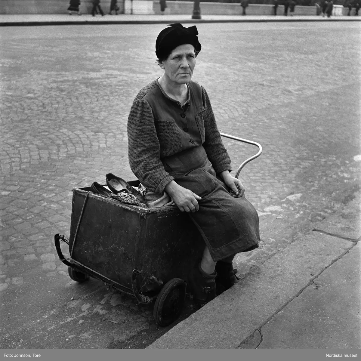 Paris. En äldre kvinna sitter i en dockvagn.